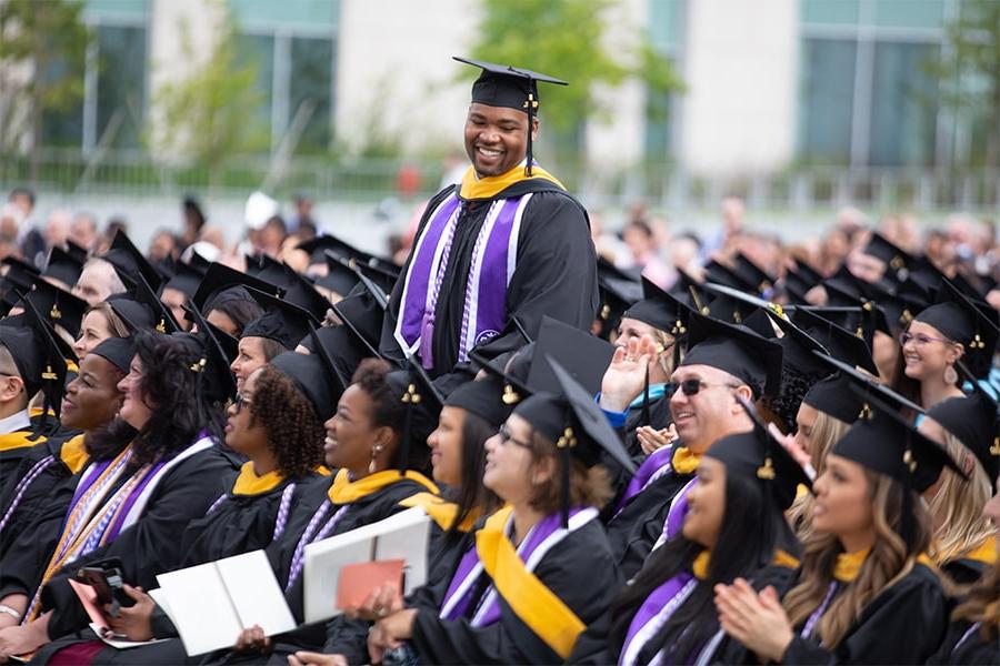 Graduate stands up in crowd at commencement